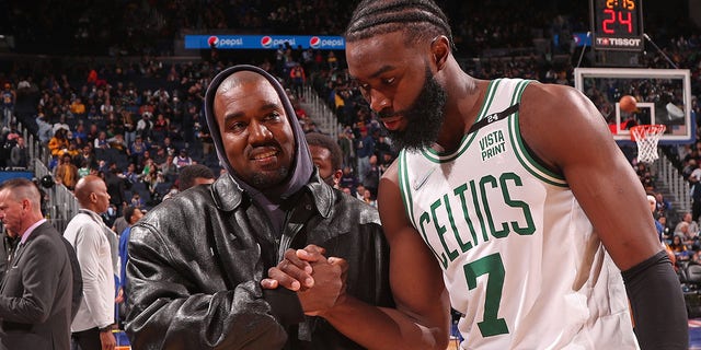 Jaylen Brown, #7 of the Boston Celtics, high-fives rapper Kanye West and his son Saint West on March 16, 2022 at Chase Center in San Francisco.