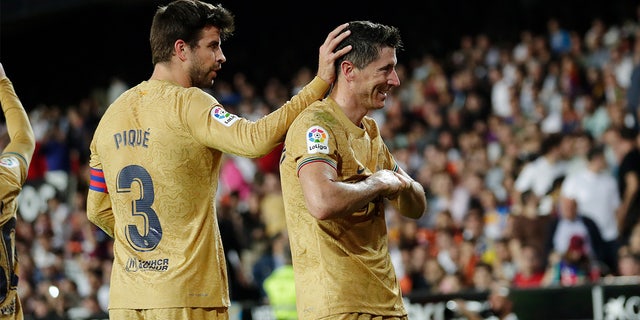 Robert Lewandowski of FC Barcelona, right, celebrating with teammate Gerard Piqué during a La Liga Santander match between Valencia and FC Barcelona at the Estadio de Mestalla Oct. 29, 2022 in Valencia, Spain.