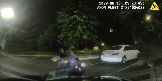 This screen grab taken from dashboard camera video provided by the Atlanta Police Department shows Rayshard Brooks, center, struggling with officers.