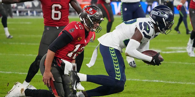 Seattle Seahawks cornerback Tariq Woolen, right, intercepts a pass intended for Tampa Bay Buccaneers quarterback Tom Brady, left, during the second half at Allianz Arena, Nov. 13, 2022, in Munich, Germany.