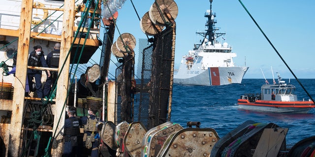 In this photo made available by the U.S. Coast Guard, guardsmen from the cutter James, seen at background right, conduct a boarding of a fishing vessel in the eastern Pacific Ocean, on Aug. 4, 2022. During the 10-day patrol for illegal, unreported or unregulated fishing, three vessels steamed away. Another turned aggressively 90 degrees toward the James, forcing the American vessel to maneuver to avoid being rammed. (Petty Officer 3rd Class Hunter Schnabel/U.S. Coast Guard via AP)