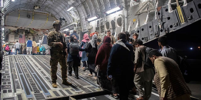 Afghan passengers board a U.S. Air Force C-17 Globemaster III during the Afghanistan evacuation at Hamid Karzai International Airport in Kabul, Afghanistan.