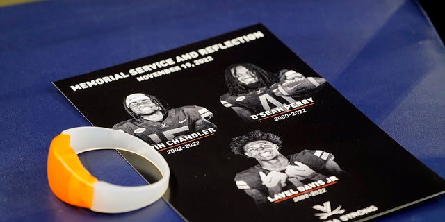 A commemorative card and light up bracelet rest on a seat before a memorial service for University of Virginia football players Lavel Davis Jr., D'Sean Perry and Devin Chandler at John Paul Jones Arena at the school in Charlottesville, Va., Saturday, Nov. 19, 2022.