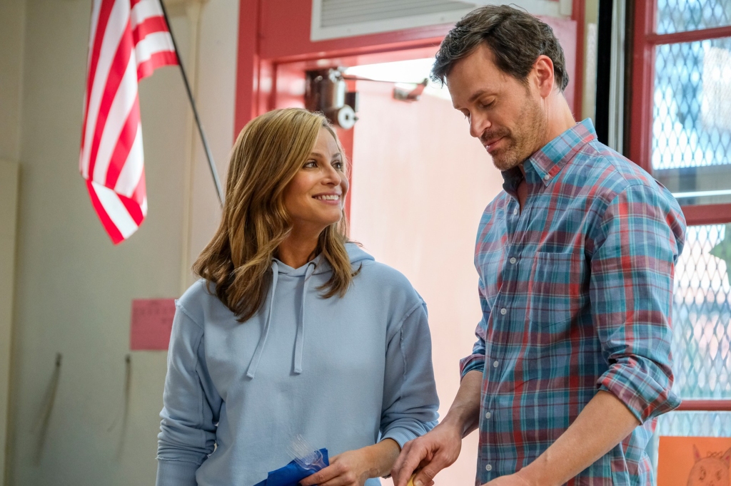 Andrea Savage and Tom Everett Scott in a scene from her Hulu series "I'm Sorry." Savage is wearing a blue sweatshirt and is smiling at Scott, who's looking down. He's wearing a plaid shirt. 