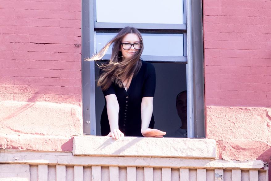 Anna Delvey looks out an apartment window.