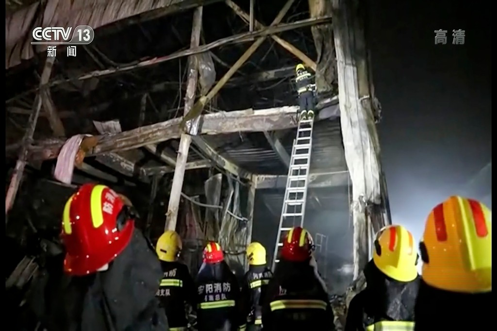 Rescuers use a ladder to climb into the remains of a fire at an industrial wholesaler in Anyang in central China's Henan province on Nov. 21, 2022.