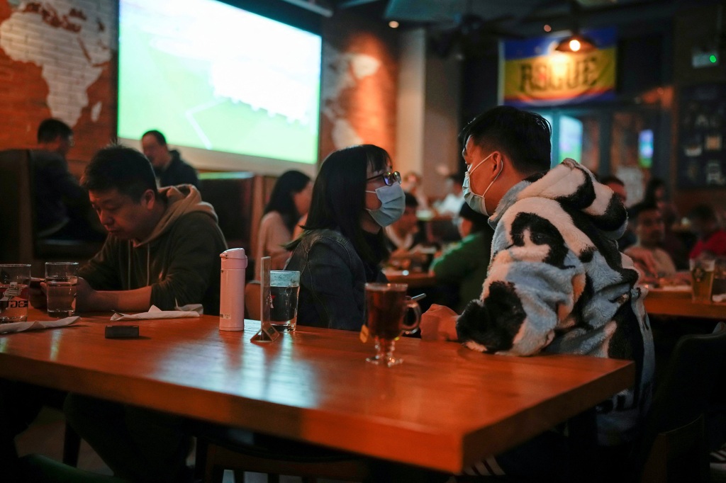 People wearing masks in a Chinese bar during a World Cup match.