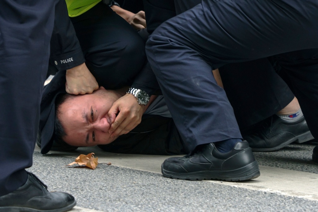Police pin down a protester in Shanghai.