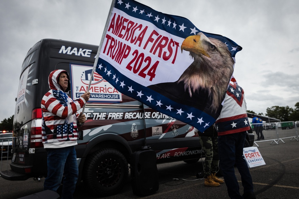 A protester waving an "America First Trump 2024" flag at a demonstration outside a temporary migrant shelter in the Bronx on Oct. 3. 