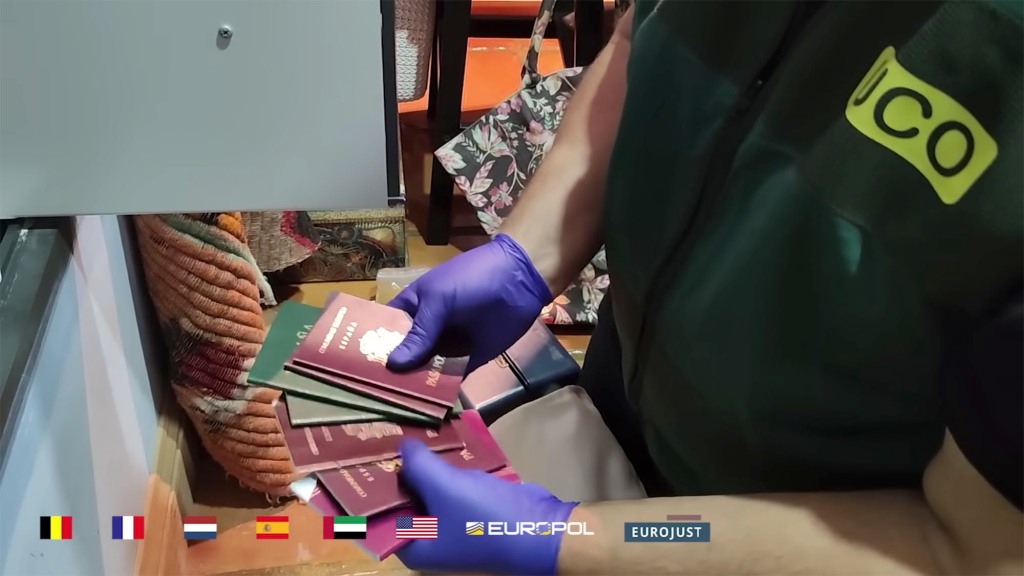 An investigator holds multiple passports seized during the raids. 