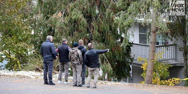 Investigators are seen searching a parking lot area behind the house in Moscow, Idaho, where four people were slain on Nov. 13.