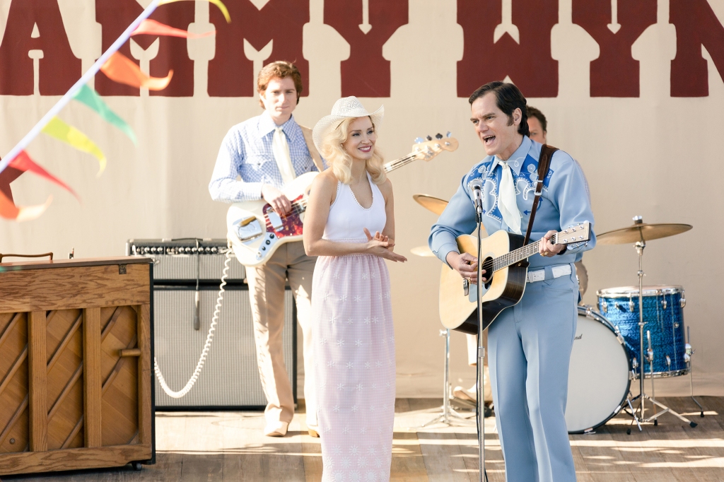 Jessica Chastain and Michael Shannon as Tammy and George performing a duet together onstage. Tammy is wearing a white cowboy hat, white shirt and pink skirt; George is dressed all in blue except for a white tie and belt. He's strumming an acoustic guitar and is in the middle of singing a song.