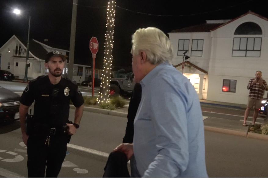 A picture of Jay Leno talking with C.A. police officers.