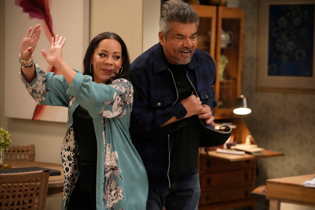 Selenis Leyva and George Lopez as Rosie and George. They're dancing together side by side in Mayan's living room.