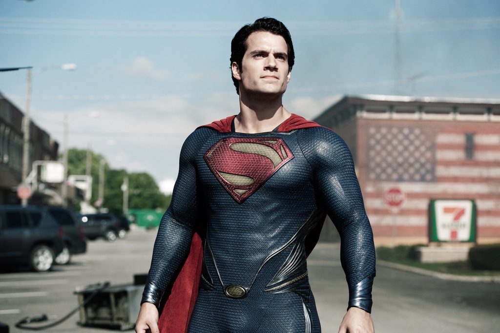Henry Cavill wearing a superman cape standing in the street. 