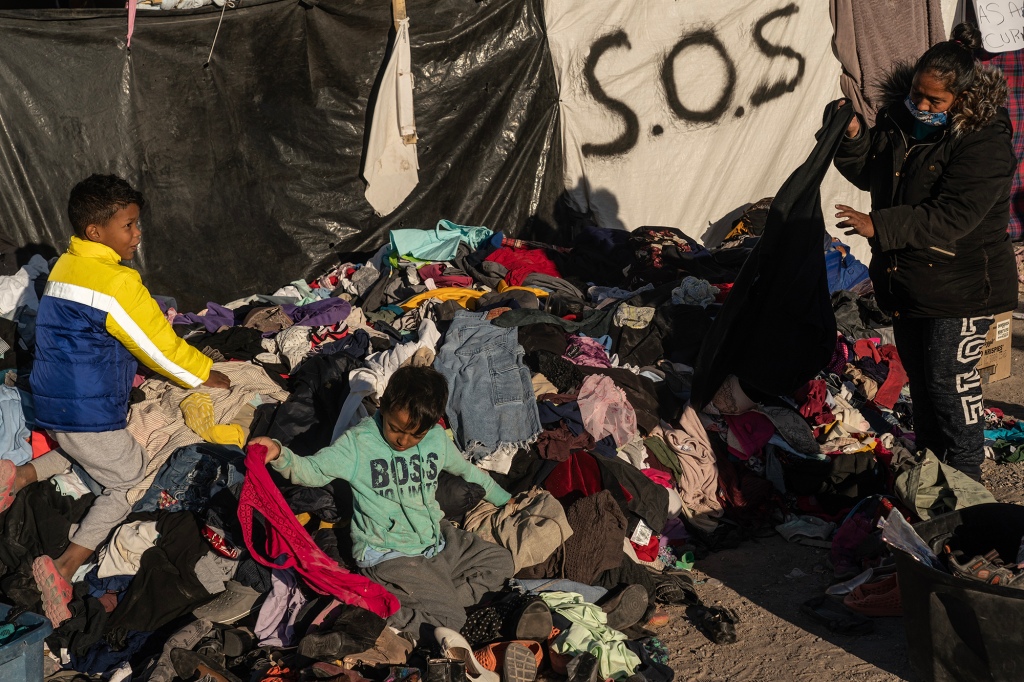 Migrants pick through a pile of donated clothes.