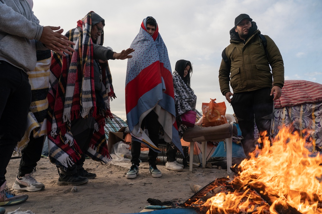 Migrants huddle for warmth before attempting to cross the border.