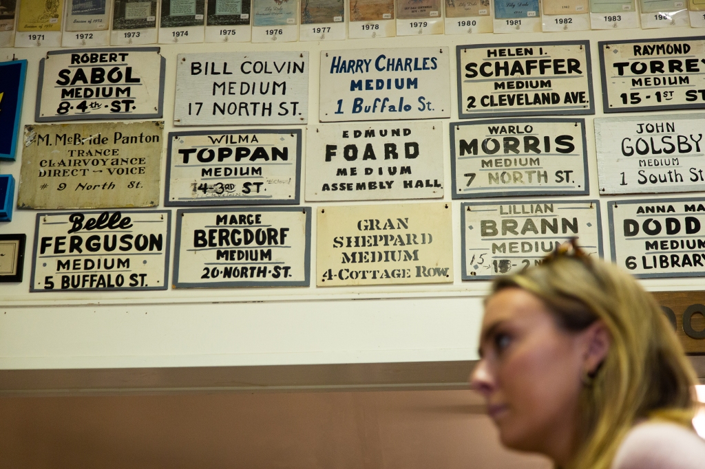 At Lily Dale Museum, Schlott walks by signs advertising psychic residents of the town from years past. 