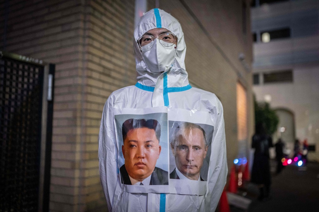 A man wearing a protective suit with portraits of North Korea's leader Kim Jong Un and Russia's President Vladimir Putin 