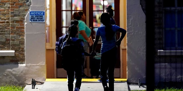 Students holds hands as they arrive at Uvalde Elementary, now protected by a fence and Texas State Troopers, for the first day of school, Tuesday, Sept. 6, 2022, in Uvalde. 