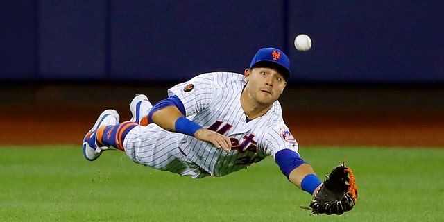 New York Mets center fielder Michael Conforto dives for but can't make a play on a ball hit by the Los Angeles Dodgers' Yasiel Puig during the eighth inning of a game June 23, 2018, in New York.