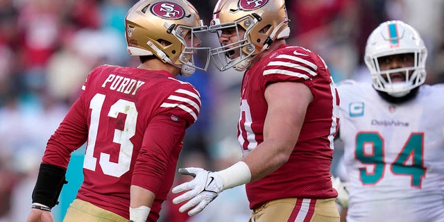 San Francisco 49ers quarterback Brock Purdy (13) celebrates after throwing a touchdown pass to running back Christian McCaffrey with offensive tackle Daniel Brunskill, middle, as Miami Dolphins defensive tackle Christian Wilkins (94) reacts during the first half of a game in Santa Clara, Calif., Sunday, Dec. 4, 2022. 