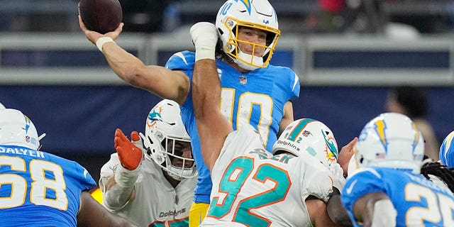 Los Angeles Chargers quarterback Justin Herbert, top, throws under pressure from Miami Dolphins defensive tackle Zach Sieler, #92, during the second half of an NFL football game Sunday, Dec. 11, 2022, in Inglewood, California.