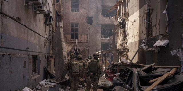 Ukrainian servicemen walk among debris of damaged buildings after a Russian attack in Kharkiv, Ukraine, Saturday, April 16, 2022. 