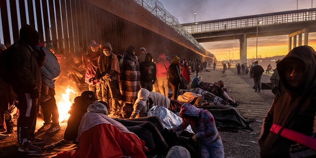 EL PASO, TEXAS - DECEMBER 22: Immigrants warm to a fire at dawn after spending the night outside next to the U.S.-Mexico border fence on December 22, 2022 in El Paso, Texas. A spike in the number of migrants seeking asylum in the United States has challenged local, state and federal authorities. The numbers are expected to increase as the fate of the Title 42 authority to expel migrants remains in limbo pending a Supreme Court decision expected after Christmas.  