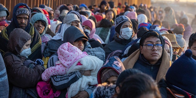 EL PASO, TEXAS - DECEMBER 22: Immigrants bundle up against the cold after spending the night camped alongside the U.S.-Mexico border fence on December 22, 2022 in El Paso, Texas. A spike in the number of migrants seeking asylum in the United States has challenged local, state and federal authorities. The numbers are expected to increase as the fate of the Title 42 authority to expel migrants remains in limbo pending a Supreme Court decision expected after Christmas.  