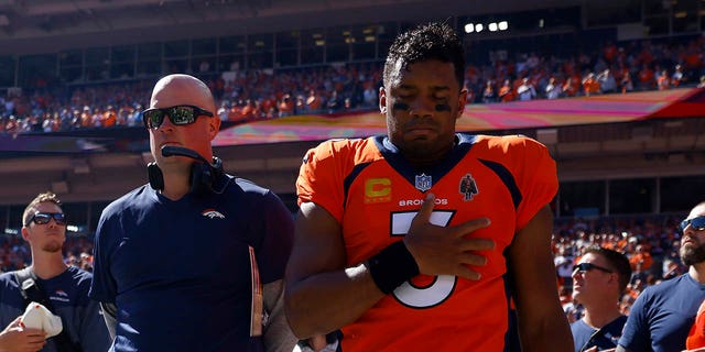 Head coach Nathaniel Hackett, left, and Russell Wilson (3) of the Denver Broncos take a moment during the national anthem prior to playing the Houston Texans at Empower Field At Mile High Sept. 18, 2022, in Denver, Colo. 