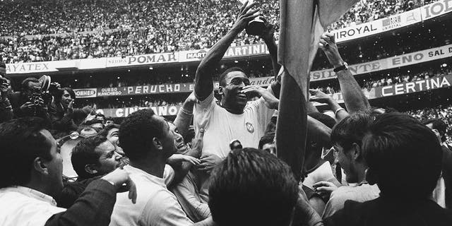 Brazil's Pelé holds up his team's Jules Rimet Trophy, or the FIFA World Cup Trophy, following Brazil's 4-1 victory over Italy at the World Cup at the Azteca Stadium in Mexico City on June 21, 1970.