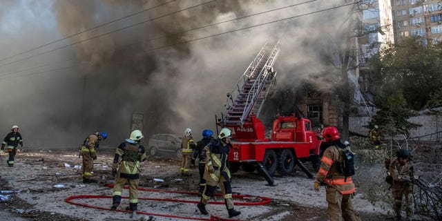 Firefighters help a local woman evacuate from a residential building destroyed by a Russian drone strike, which local authorities consider to be Iranian-made unmanned aerial vehicles, Shahed-136, amid Russia's attack on Ukraine, in Kyiv, Ukraine October 17, 2022. 