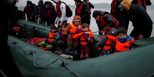 A group of more than 40 migrants with children get on an inflatable dinghy, as they leave the coast of northern France to cross the English Channel, near Wimereux, France, Nov. 24, 2021. 