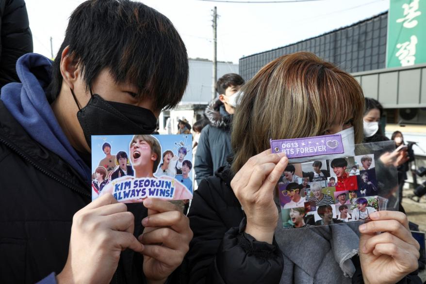 Fans hold up cards with pictures on it as, they wait for the arrival of Jin outside a South Korean army boot camp in Yeoncheon, South Korea on Dec. 13, 2022.