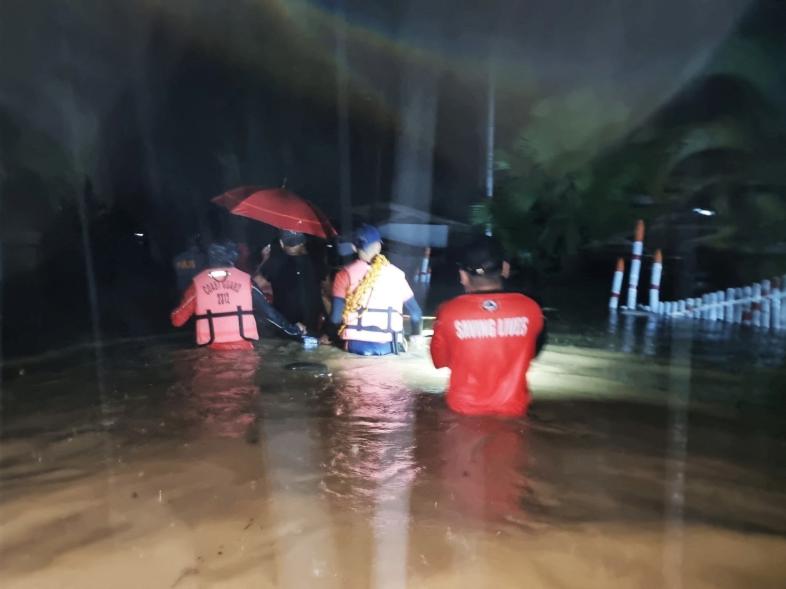 Members of the Philippine Coast Guard wade through a flooded street during a rescue operation, in Isabela, Basilan province, Philippines on Dec. 27, 2022.