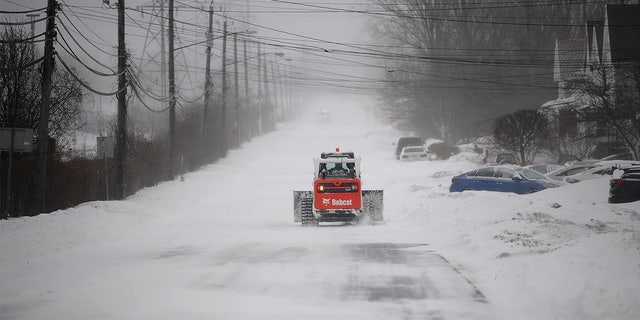 Bobcat makes its way to help dig out abandoned vehicles along the Lake Erie shoreline on December 24, 2022, in Hamburg, New York.