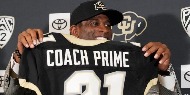 Deion Sanders holds up a jersey after being introduced as the new head football coach at the University of Colorado during a news conference Dec. 4, 2022, in Boulder, Colo.  