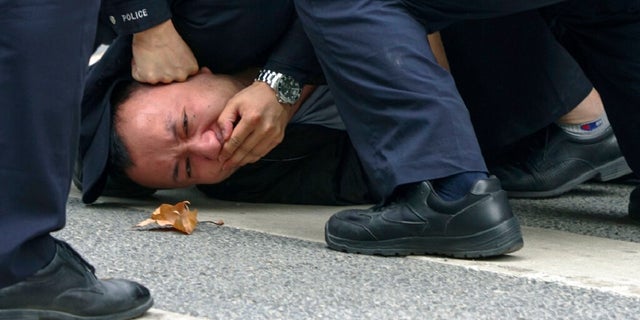 Policemen pin down and arrest a protester during a protest on a street in Shanghai. Authorities eased antivirus rules in scattered areas but affirmed China's severe "zero-COVID" strategy Monday after crowds demanded President Xi Jinping resign during protests against controls that confine millions of people to their homes. 