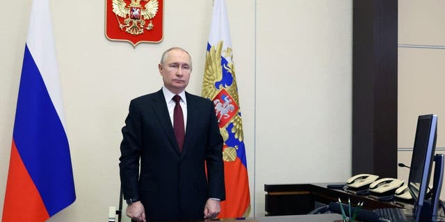 Russian President Vladimir Putin listens to the national anthem as he oversees the commissioning of new ships for the Russian navy via video conference at the Novo-Ogaryovo residence outside Moscow, Russia, Thursday, Dec. 29, 2022. 