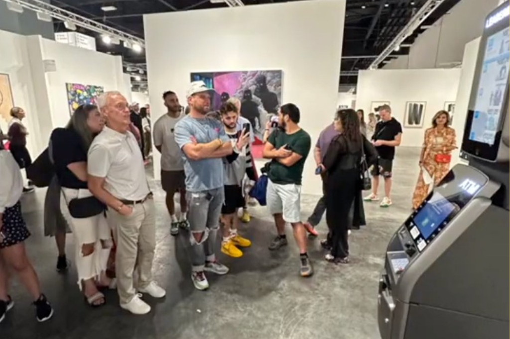 People gather around looking at the leaderboard of the richest and poorest at Art Basel. 