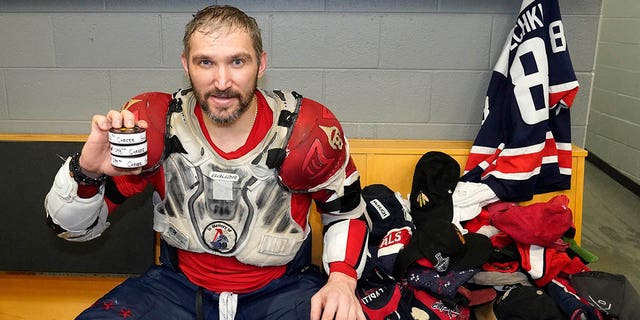 Washington Capitals' Alex Ovechkin holds his 798, 799 and 800th career goal pucks in the locker room after the Blackhawks game, Tuesday, Dec. 13, 2022, in Chicago.