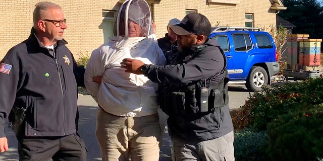 Rorie S. Woods, 55, of Hadley, Mass., center, wears a beekeeping suit while taken into custody by Hampden County Sheriff's Department officers, in Longmeadow, Mass. Woods is accused of unleashing bees on sheriff's deputies serving an eviction notice, one of many bizarre crimes in 2022. 