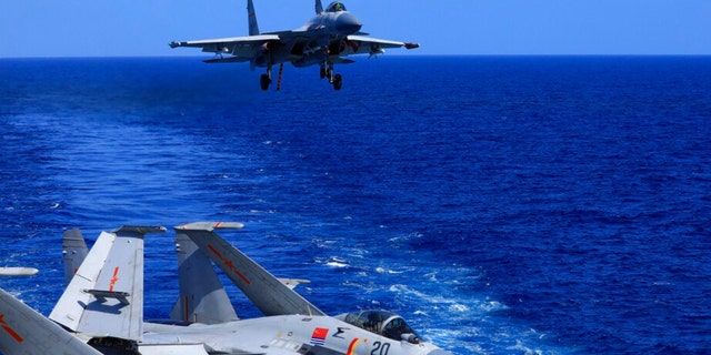 In this photo released Dec. 31, 2021 by Xinhua News Agency, an undated photo shows a carrier-based J-15 fighter jet preparing to land on the Chinese navy's Liaoning aircraft-carrier during open-sea combat training.  China is holding military exercises in the disputed South China Sea coinciding with U.S. President Joe Biden’s visits to South Korea and Japan that are largely focused on countering the perceived threat from China. 