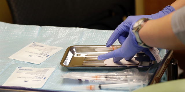 A health care worker prepares syringes, including a vaccine for measles, mumps, and rubella (MMR), for a child's inoculations at the International Community Health Services in Seattle. Officials in the Pacific Northwest say a measles outbreak that sickened multiple people is over.