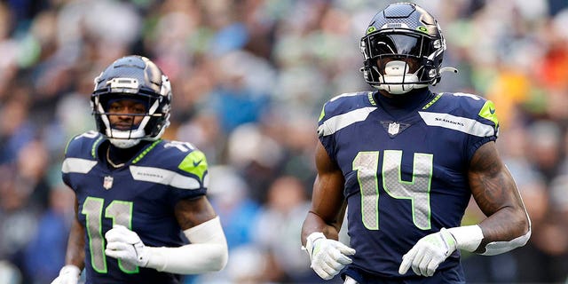 Marquise Goodwin, #11, and DK Metcalf, #14 of the Seattle Seahawks, jog to their positions during the third quarter against the Carolina Panthers at Lumen Field on Dec. 11, 2022 in Seattle.