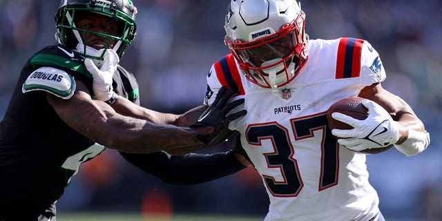 Damien Harris #37 of the New England Patriots runs with the ball as D.J. Reed #4 of the New York Jets defends during the first half at MetLife Stadium on October 30, 2022 in East Rutherford, New Jersey.