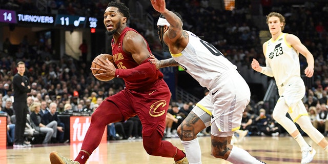 Cleveland Cavaliers guard Donovan Mitchell, left, drives against Utah Jazz guard Jordan Clarkson during the second half of an NBA basketball game, Monday, Dec. 19, 2022, in Cleveland. 