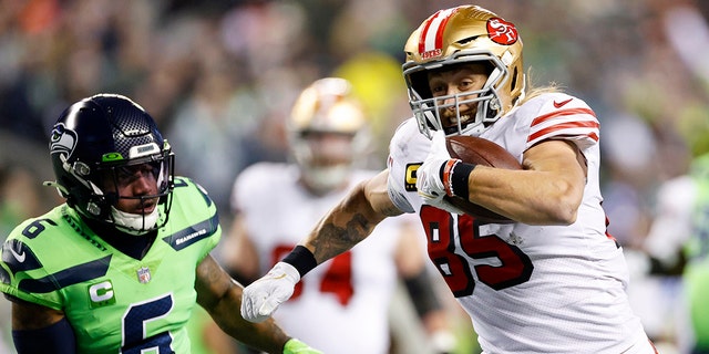 George Kittle #85 of the San Francisco 49ers carries the ball for a touchdown against the Seattle Seahawks during the first quarter of the game at Lumen Field on December 15, 2022 in Seattle, Washington.