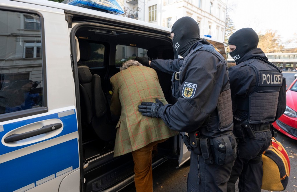 Masked police officers lead an arrested suspect to a police vehicle during a raid in Frankfurt, Germany on Dec. 7, 2022.